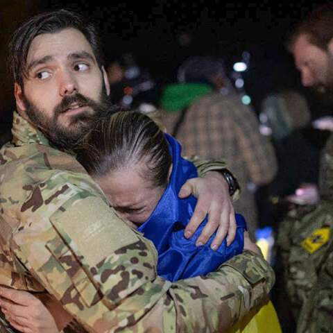 Μητέρα με την ουκρανική σημαία στην πλάτη κλαίει στην αγκαλιά του γιου της, ο οποίος αφέθηκε ελεύθερος από τους Ρώσους στο πλαίσιο της ανταλλαγής αιχμαλώτων