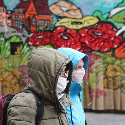 Άνθρωποι με μάσκα για τον κορωνοϊό μπροστά από mural για την πανδημία covid στο Σεράγεβο