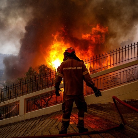 Πυροσβέστης μπροστά από φωτιά με τα χέρια που προδίδουν την ένταση