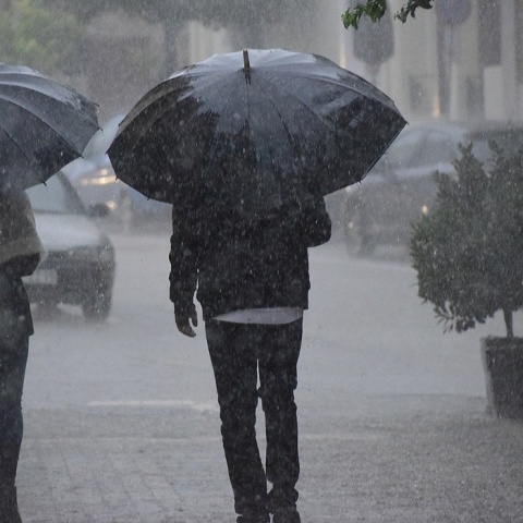 Δύο άτομα με ομπρέλες εν μέσω καταιγίδας