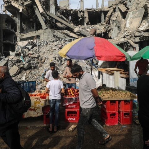 Διάφοροι Παλαιστίνιοι περνούν μπροστά από πάγκους με τρόφιμα που έχουν στηθεί δίπλα σε κατεστραμμένα κτίρια την τελευταία Παρασκευή του Ραμαζανιού κατά μήκος ενός δρόμου στον προσφυγικό καταυλισμό Al Nusairat, στη Λωρίδα της Γάζας