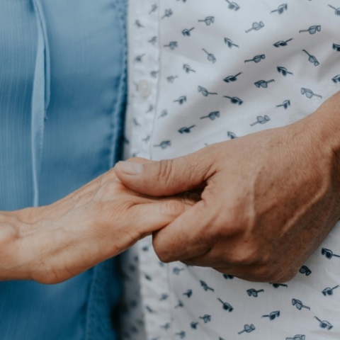 Δύο γυναίκες μεγάλης ηλικίας κρατάνε η μία το χέρι της άλλης φορώντας μπλε και άσπρο φόρεμα αντίστοιχα χωρίς να φαίνονται πρόσωπα