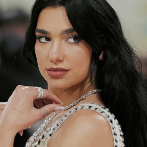 Η Dua Lipa σε κοντινό πλάνο φορώντας άσπρο φόρεμα και κοσμήματα