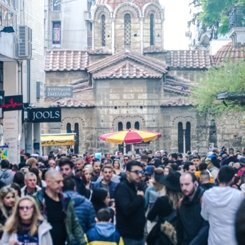 Πλήθος κόσμου περπατάει στην Ερμού μπροστά από μαγαζιά - Στο βάθος η εκκλησία Καπνικαρέα
