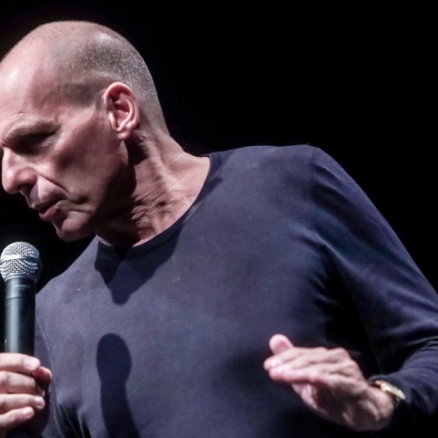 Ο Γιάννης Βαρουφάκης μιλάει όρθιος με μικρόφωνο