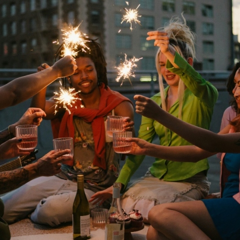 Έξι άτομα καθισμένα υψώνουν τα ποτήρια τους κρατώντας κεριά