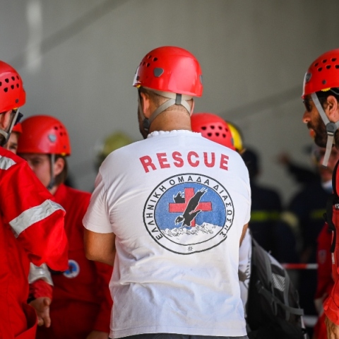 Διασώστες φορώντας κόκκινες στολές και άσπρη μπλούζα με κράνη και σακίδιο