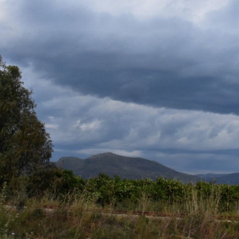 Βουνά, σύννεφα, δέντρα και στύλος της ΔΕΗ