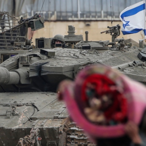 Παλαιστίνιος κουβαλώντας ρούχα μπροστά από τανκ του Ισραήλ