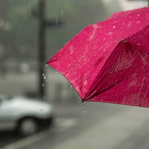 Χέρι κρατάει κόκκινη ομπρέλα στη βροχή