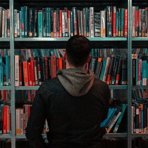 Άνδρας όρθιος μπροστά από βιβλιοθήκη γεμάτη βιβλία