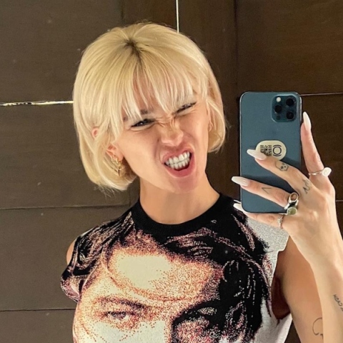 Ξανθιά γυναίκα κρατάει κινητό τηλέφωνο και χαμογελάει