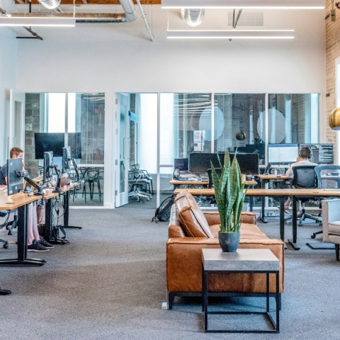 Αίθουσα με τραπέζια, καρέκλες, γραφεία, εργαζόμενους, γλάστρα