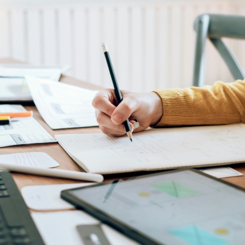 χέρι κρατάει μολύβι πάνω από τραπέζι με έγγραφα