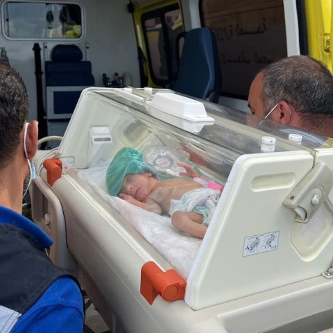 2 άνδρες κουβαλάνε θερμοκοιτίδα με βρέφος