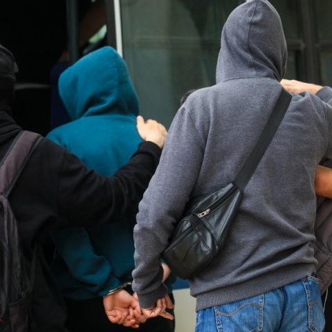 4 άνδρες με κουκούλες μπαίνουν σε όχημα αστυνομίας