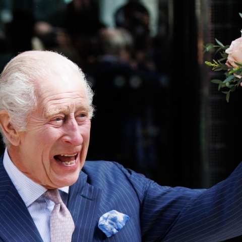 Άνδρας με ριγέ μπλε σακάκι χαμογελάει κρατώντας λουλούδια