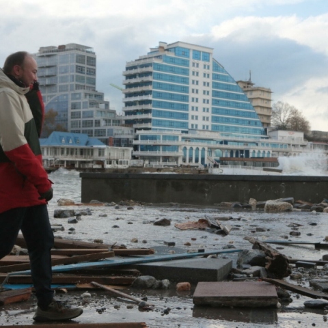 ανδρας περπαταει μπροστα απο κατεστραμμενα κτηρια