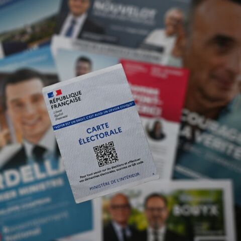 Κάρτα για την άσκηση του εκλογικού δικαιώματος στη Γαλλία με φόντο τα φυλλάδια των υποψηφίων