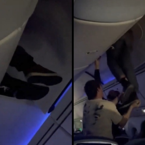 εσωτερικο αεροπλανου, επιβατες βοηθουν ανδρα να ξεκολλησει απο ντουλάπι χειραποσκευών