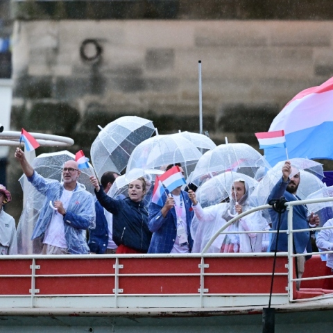 γαλλοι αθλητες σε βαρκα με αδιαβροχα, σημαιες και ομπρελες