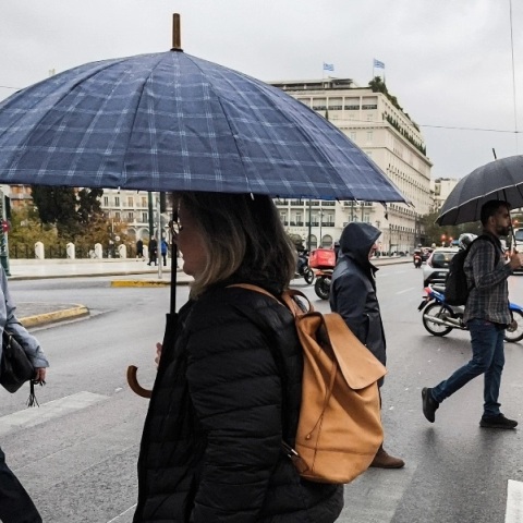 κοσμος περπαταει κρατώντας ομπρελες