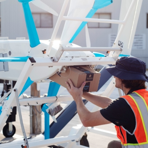 εργαζομενος φορτωνει δεμα σε drone παραδοσης