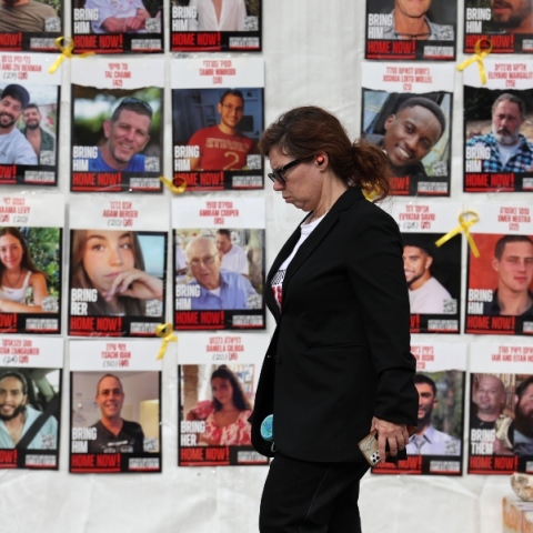 γυναικα περπαταει μπροστα απο τα προτραιτα ομηρων της Χαμάς