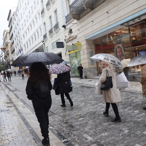 Πολίτες με ομπρέλες περπατούν υπό βροχή στην Ερμού