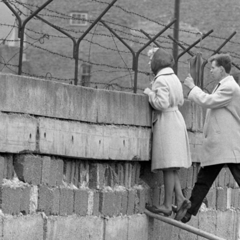21 Απριλίου, 1962 | Μια νεαρή γυναίκα, συνοδευόμενη από τον φίλο της, στέκεται στην κορυφή του Τείχους του Βερολίνου για να μιλήσει με τη μητέρα της στην πλευρά του Ανατολικού Βερολίνου