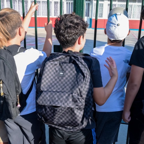 Μαθητές με τις τσάντες τους στην πλάτη αναμένουν να ανοίξει η πόρτα του σχολείου τους