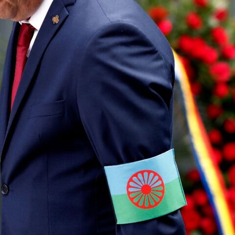 Άνδρας με τη σημαία των Ρομά ως περιβραχιόνιο, αποτίει φόρο τιμής στη τελετή μνήμης του Ολοκαυτώματος των Ρομά, στη Ρουμανία