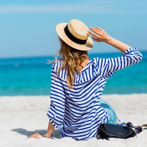 Γυναίκα με ψάθινο καπέλο στην παραλία