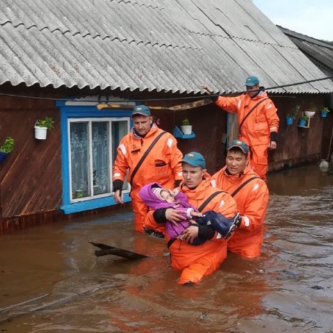 Mέλη του ρωσικού Υπουργείου Έκτακτης Ανάγκης μεταφέρουν ένα παιδί από πλημμυρισμένο σπίτι 