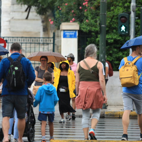 Πολίτες με ομπρέλα περπατούν εν μέσω βροχοπτώσεων