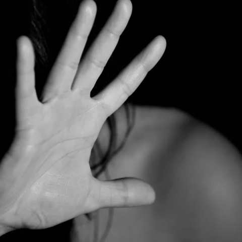 Γυναίκα προστατεύει με τα χέρια της το πρόσωπό της από τον κακοποιητή της