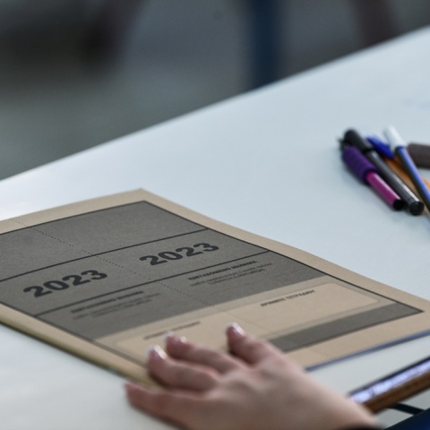 Τετράδιο εξετάσεων και παραταγμένα στιλό σε θρανίο για τις Πανελλήνιες 2023