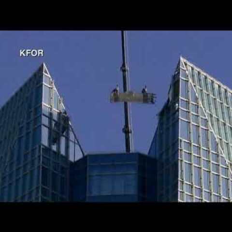 Window washers trapped in basket swinging at top of tower