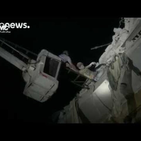 Boy hangs from rubble of building destroyed by airstrike, Aleppo