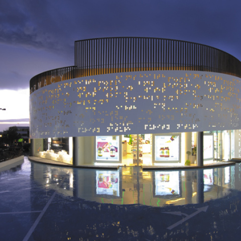 Placebo Pharmacy, Λεωφ. Βουλιαγμένης. «…Τα μεταλλικά πανέλα της πρόσοψης είναι διάτρητα με λέξεις γραμμένες με το σύστημα Μπράιγ, το οποίο χρησιμοποιείται στα φαρμακευτικά προϊόντα…»