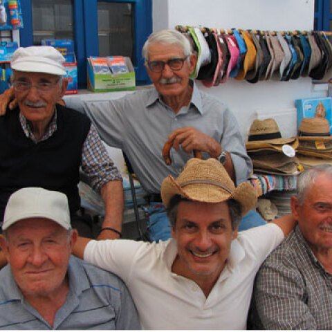 Ο Dimitris Dassios καθισμένος στο παγκάκι ανάμεσα σε φίλους στο νησί