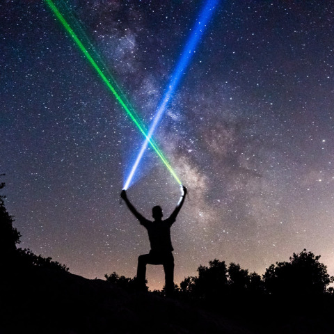 man-wielding-blue-and-green-lightsabers-in-the-starry-night-sky.jpg