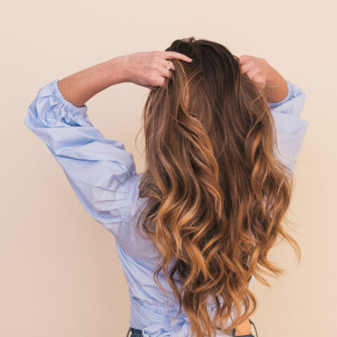 woman wearing gray dress shirt standing near white wall