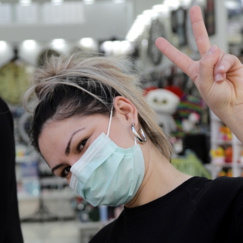 Κοπέλα με μάσκα κάνει το σήμα της νίκης 