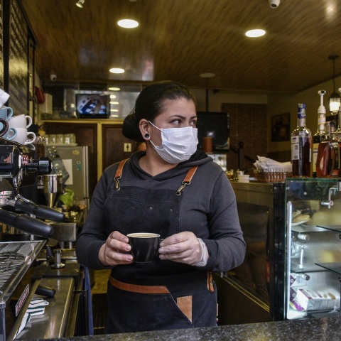 Γυναίκα με προστατευτική μάσκα και γάντια σε καφέ