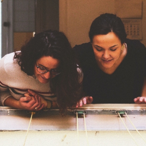 Δύο γυναίκες χαρούμενες μιλούν από το μπαλκόνι τους λόγω καραντίνας