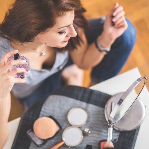 Γυναίκα κρατάει άρωμα και προϊόντα μακιγιάζ