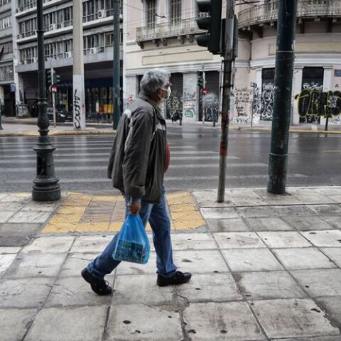 Άνδρας στο βροχερό κέντρο της Αθήνας με μάσκα