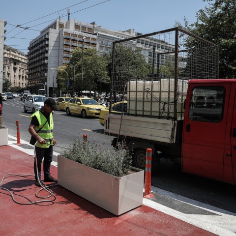 Εργάτης του δήμου ποτίζει λουλούδια σε ζαρντινιέρα στον "Μεγάλο Περίπατο" στο κέντρο της Αθήνας 