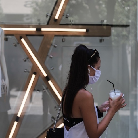 Μία κοπέλα με μάσκα και καφέ